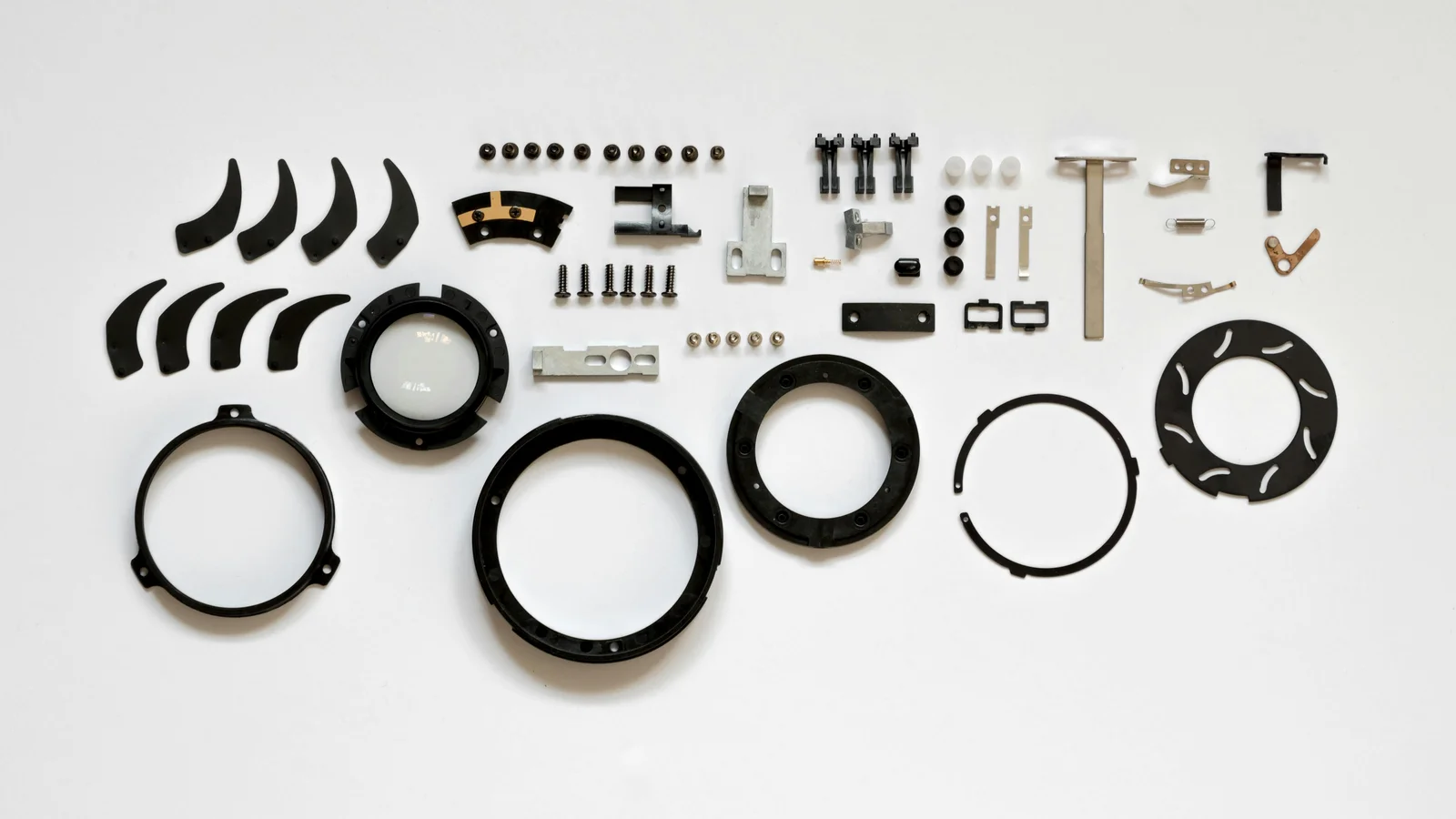 A neatly organised flat lay of mechanical components on a white surface, arranged like a parts catalogue for a configurable product line.