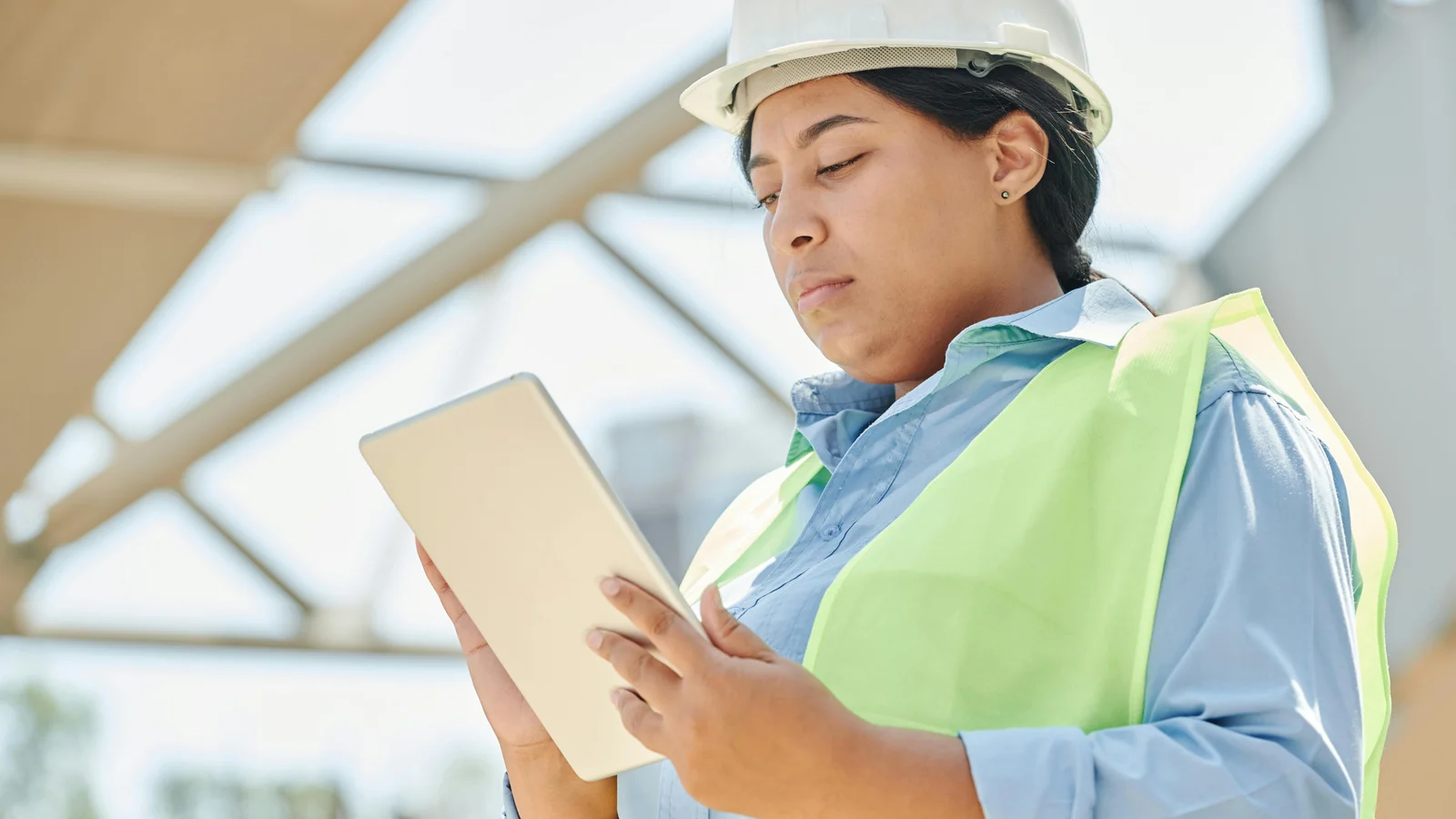 An outdoor living contractor in a hard hat reviewing a configuration on a tablet on a residential job site.