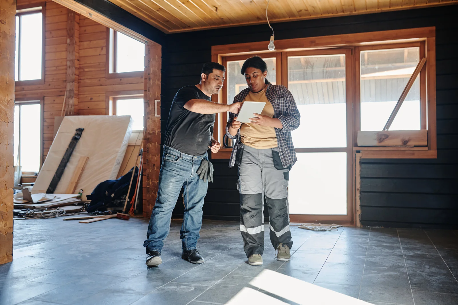 Two outdoor living trades people in a residential property reviewing a configuration on a digital tablet together.