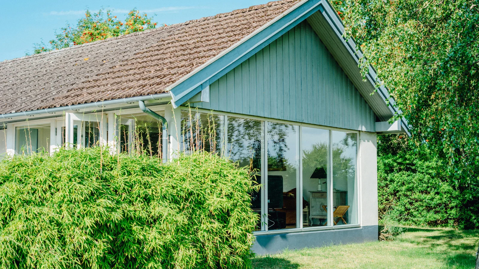Modern garden room with full-height glass panels nestled in a leafy back garden, the type of build a UK homeowner configures online before booking a site survey.