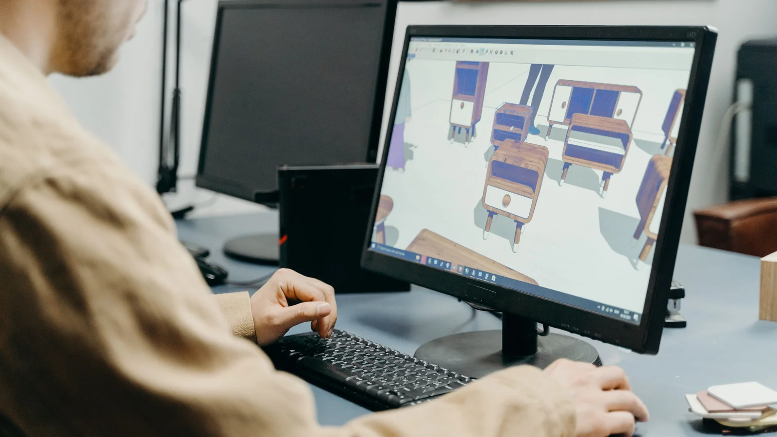 A product designer rotating a 3D furniture model on a desktop screen, the same kind of view an online shopper sees inside a product configurator.