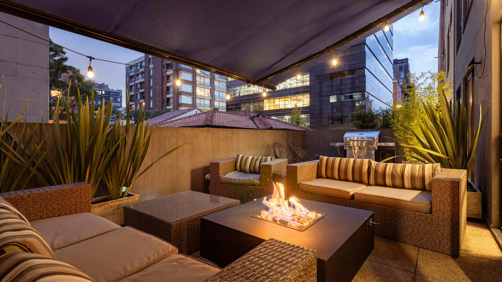 A cozy outdoor patio at twilight with elegant lounge furniture, soft lighting, and a glowing fire pit, the kind of premium residential outdoor space sold by high margin outdoor living teams.