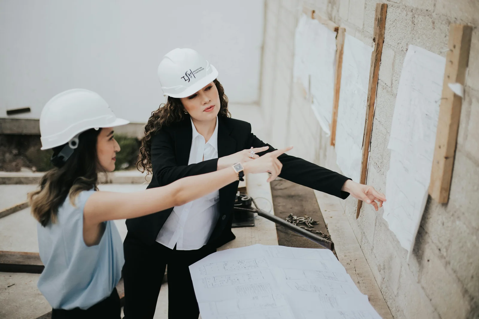 Two architects standing outdoors over a roll of building plans, talking through the design before the build starts.
