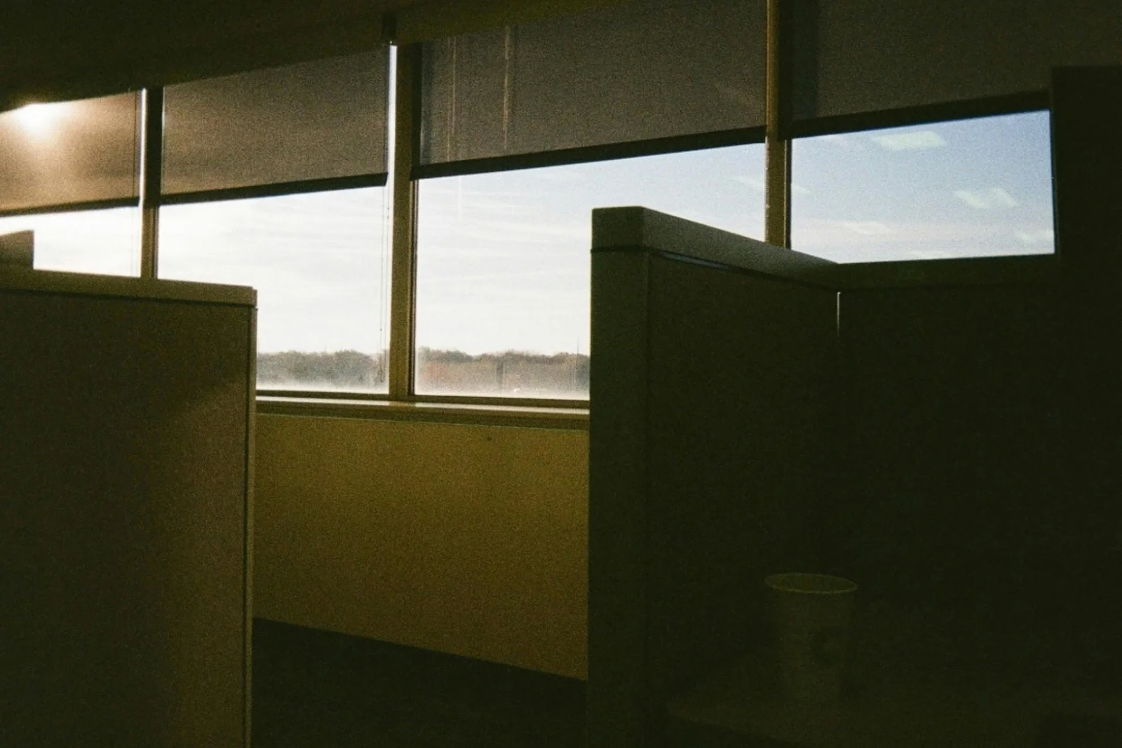 An empty office cubicle at sunrise with a window view, the scene of a Monday morning inbox waiting for someone to arrive.