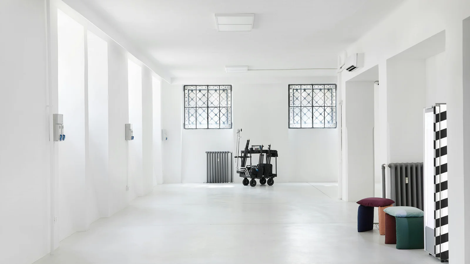 Spacious minimalist white showroom interior with modern decor, bright daylight, no merchandise on display.