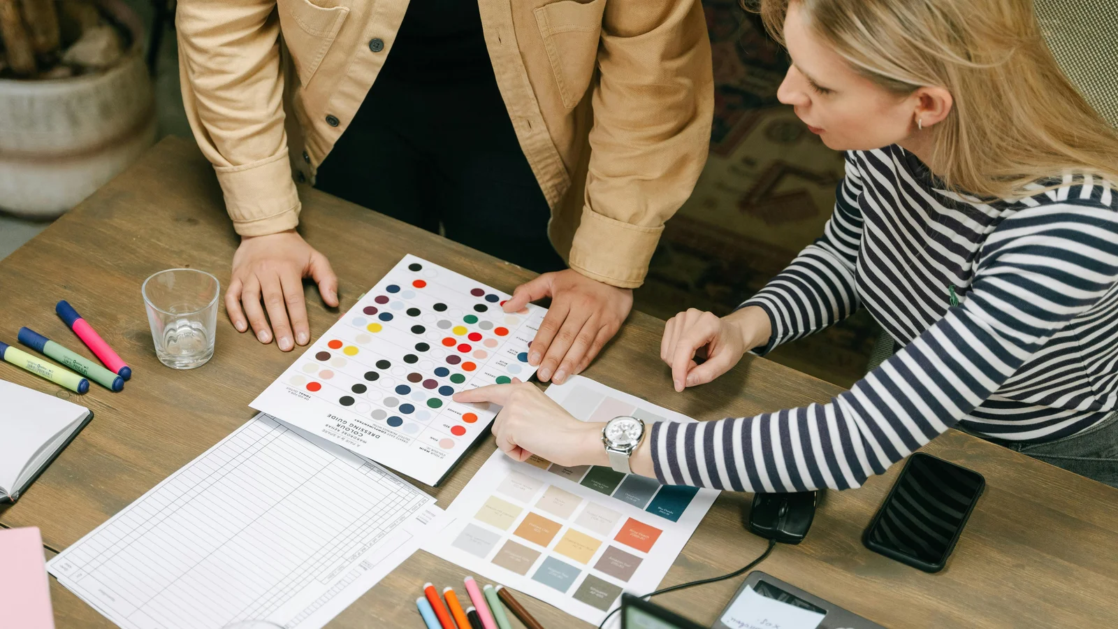 A collaborative workspace with planning sheets, colour charts, and a price list spread out as a team walks through a configuration sequence.